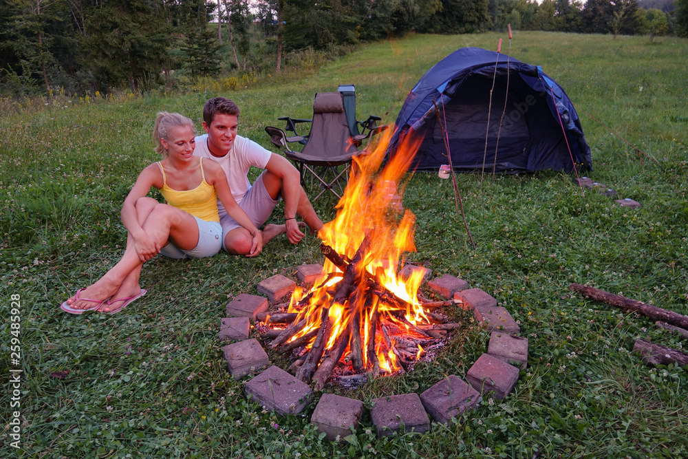 CLOSE UP: Carefree woman snuggles up to her boyfriend while sitting by the fire.