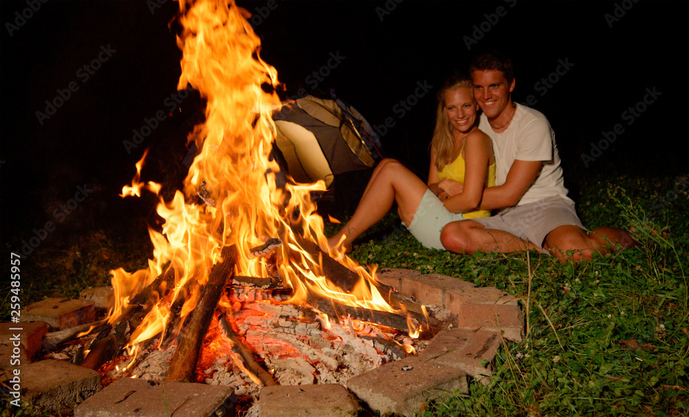 特写：美丽的女孩在温暖的篝火旁与男友拥抱。