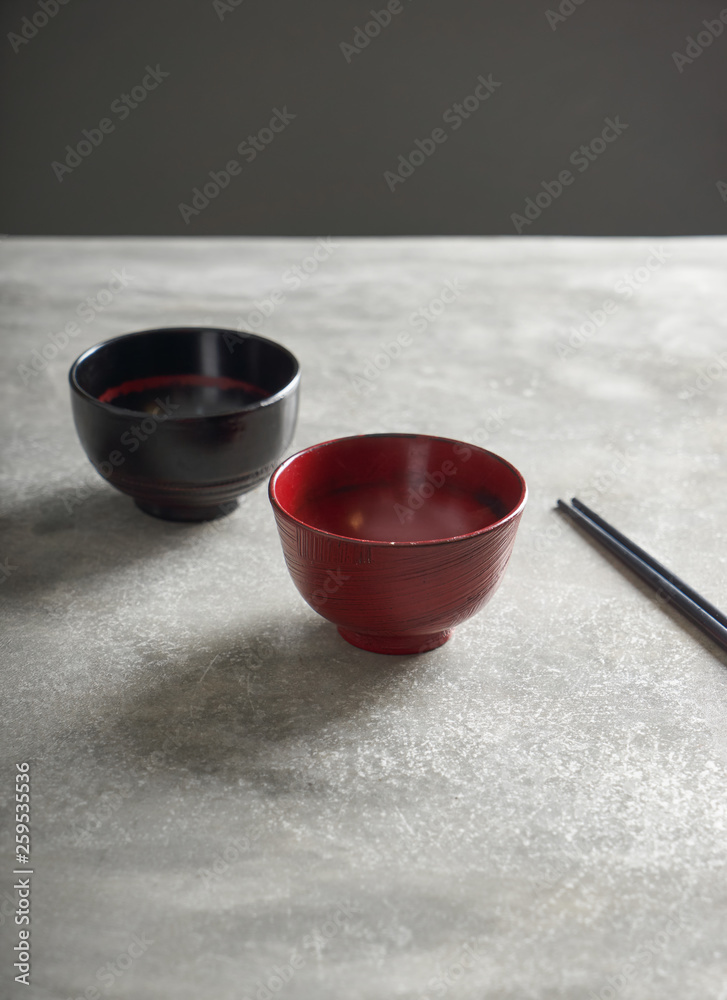 水泥桌面上的红黑碗，筷子，亚洲美食概念。