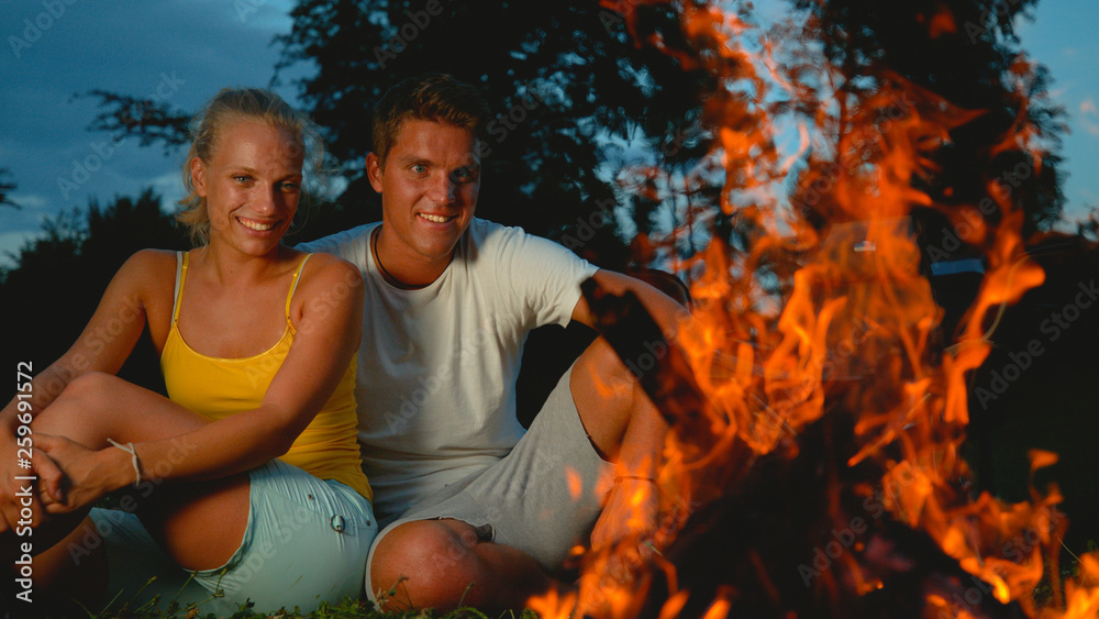 特写：一对幸福的情侣在露营旅行中坐在噼啪作响的炉火旁。