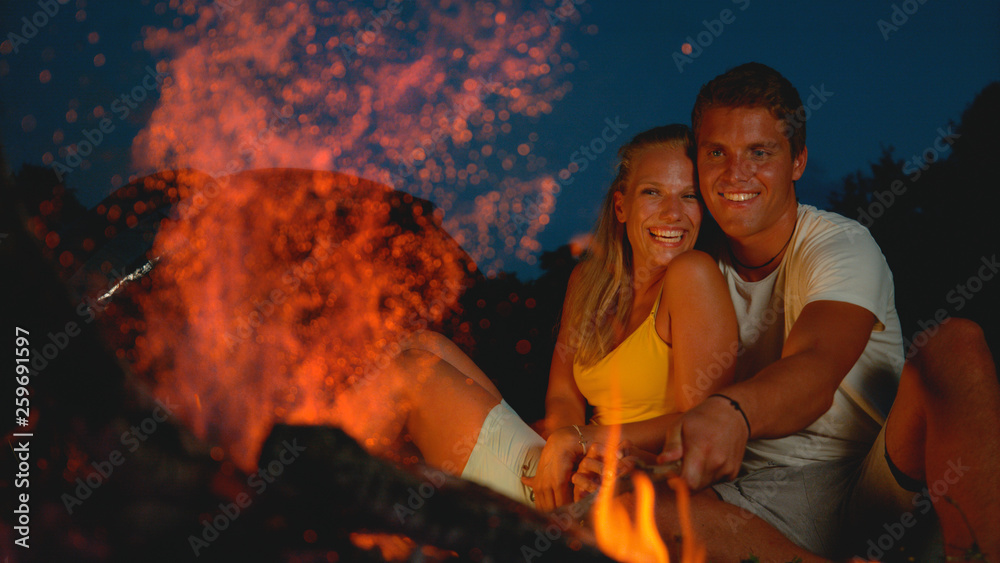 特写，自由度：一对快乐的情侣坐在篝火旁享受浪漫的夜晚。