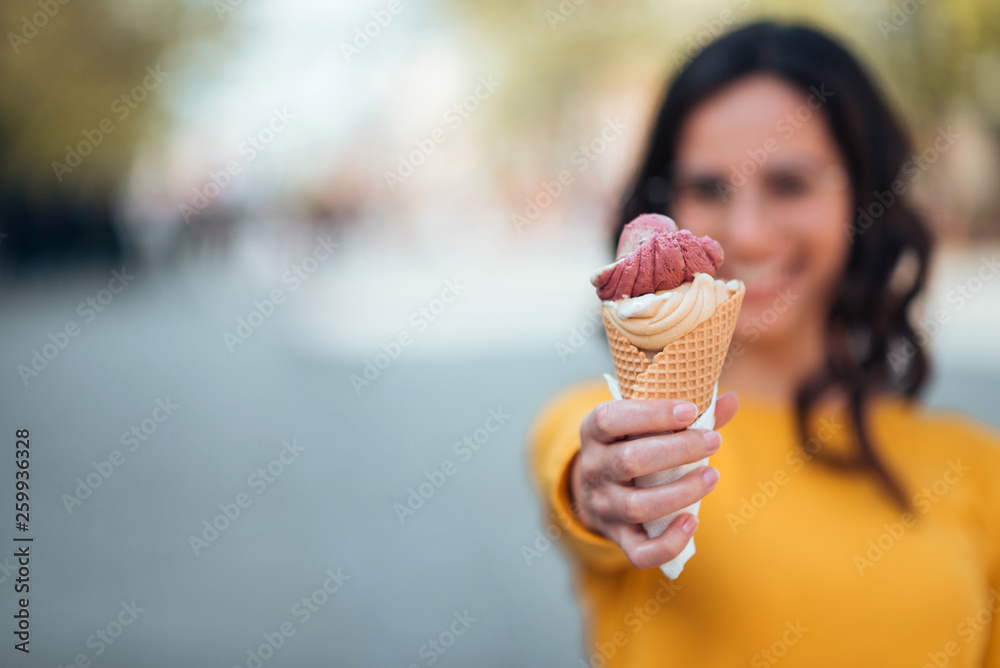 女孩拿着冰淇淋筒对着户外的相机，聚焦在前景，复制空间。