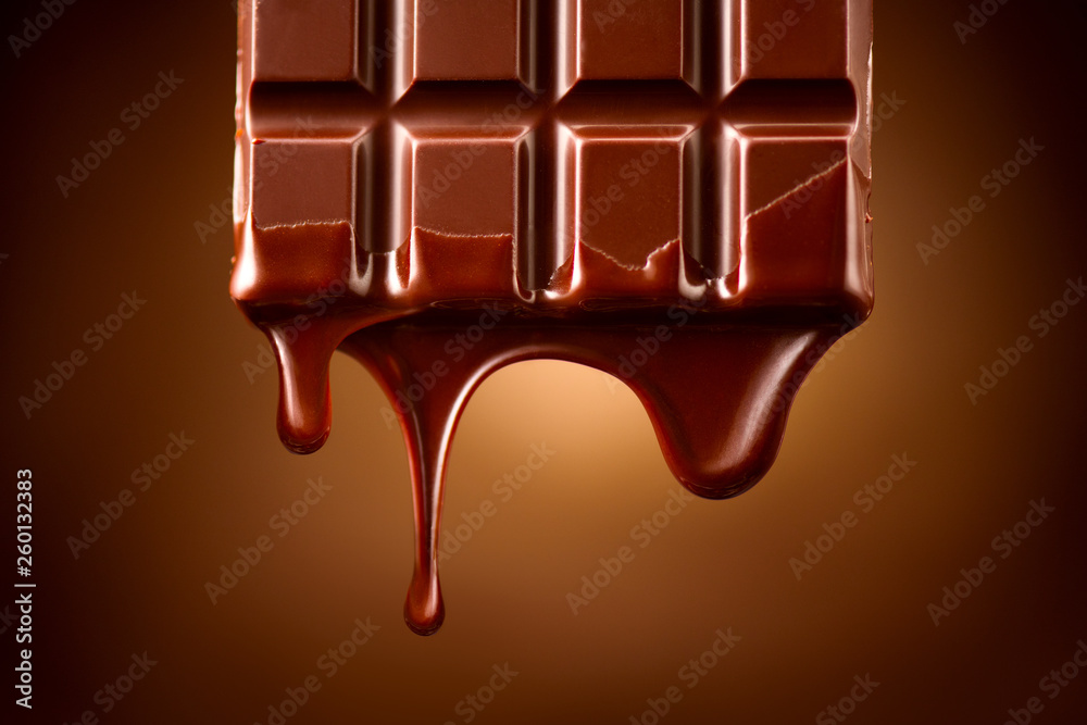 巧克力条，融化的黑巧克力滴在深棕色背景上。糖果概念