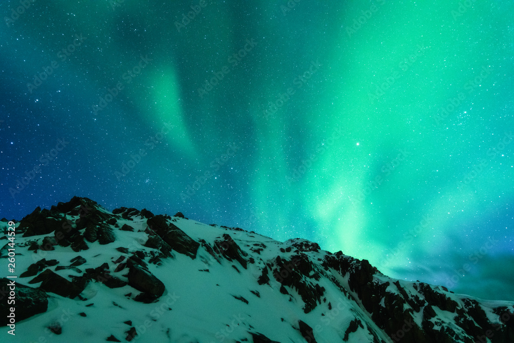 欧洲白雪皑皑的山脉上的北极光。冬天的北极光，夜晚。