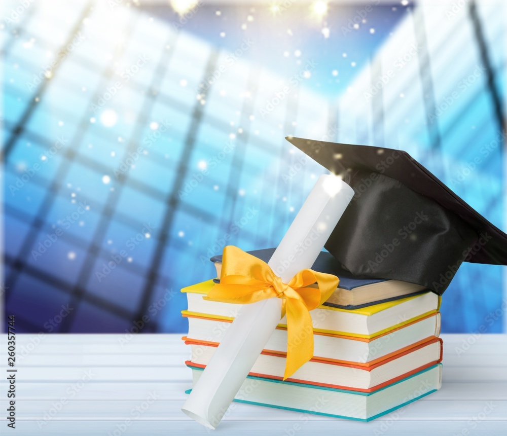 Graduation mortarboard on top of stack of books on  background