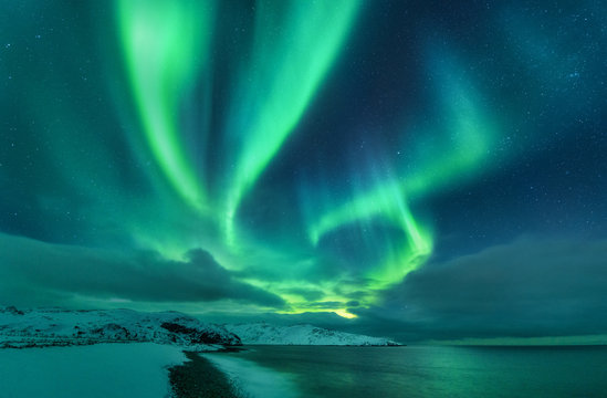 Aurora borealis over ocean. Northern lights in Teriberka, Russia. Starry sky with polar lights and c