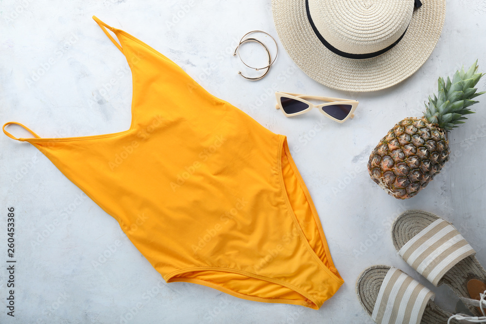 浅色背景的女性泳衣、帽子、菠萝和沙滩鞋。旅行理念