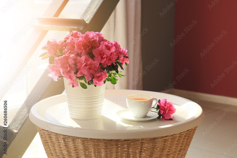 桌上摆着盛开的美丽杜鹃花和一杯茶