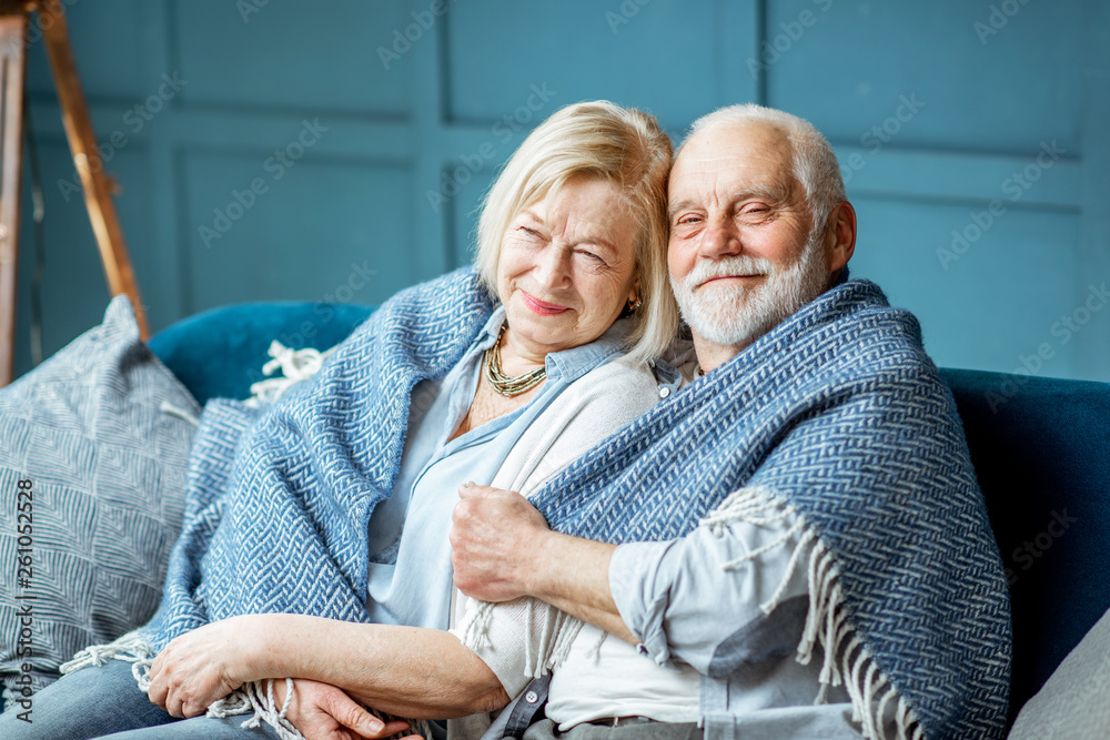 一对可爱的老年夫妇穿着格子布坐在沙发上，感觉舒适温暖。