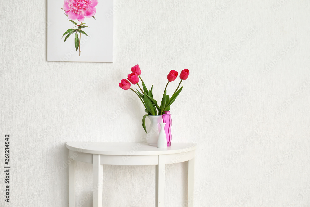 房间白墙附近摆满鲜花和装饰的桌子