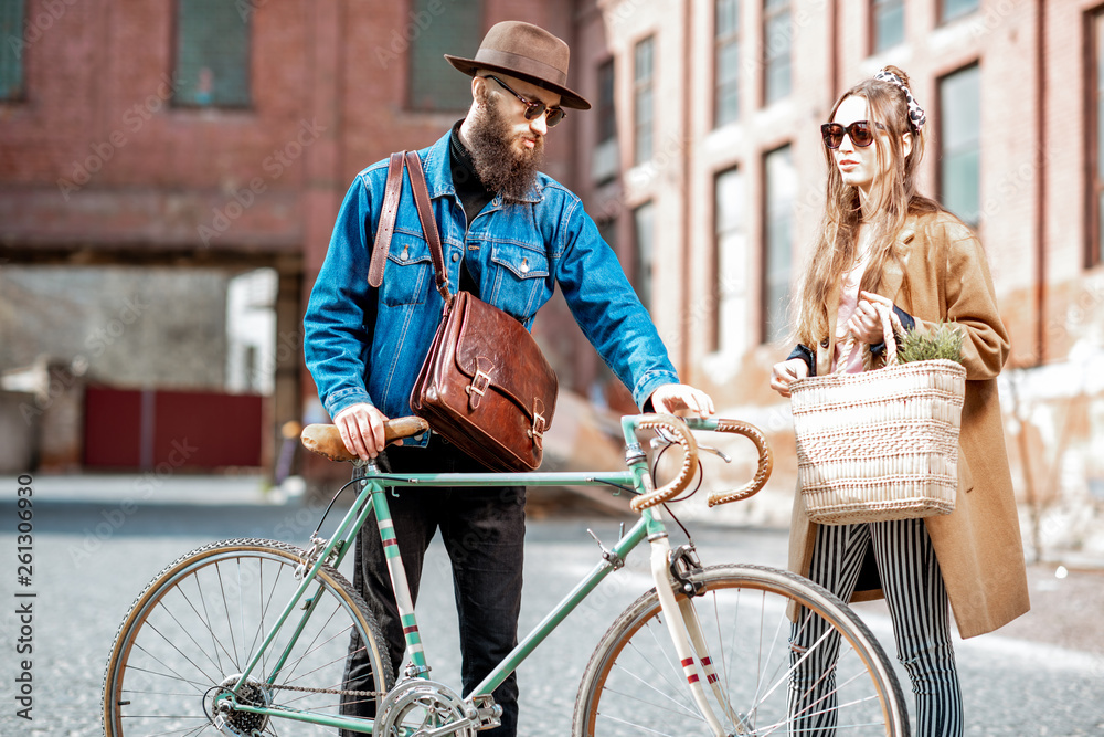Stylish young man and woman having a conversation standing together with retro bicycle outdoors on t