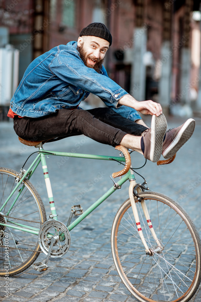时尚男人，一个疯狂的潮人，在工业城市的户外骑复古自行车，玩得很开心