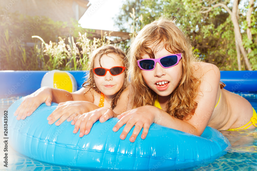 Two girls swimming in the pool with  rubber ring