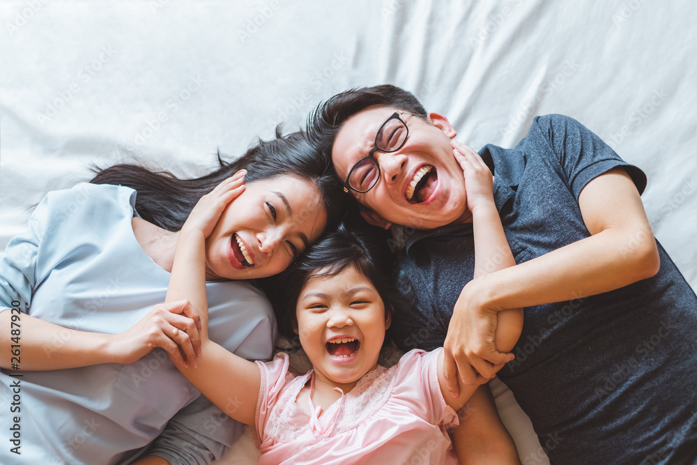快乐的亚洲家庭躺在床上微笑，俯视图