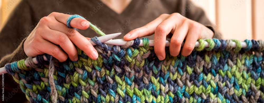 A woman knits from thick yarn.