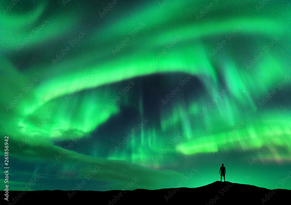 北极光和站着的人的剪影。挪威罗弗敦群岛。极光和快乐的人。天空w