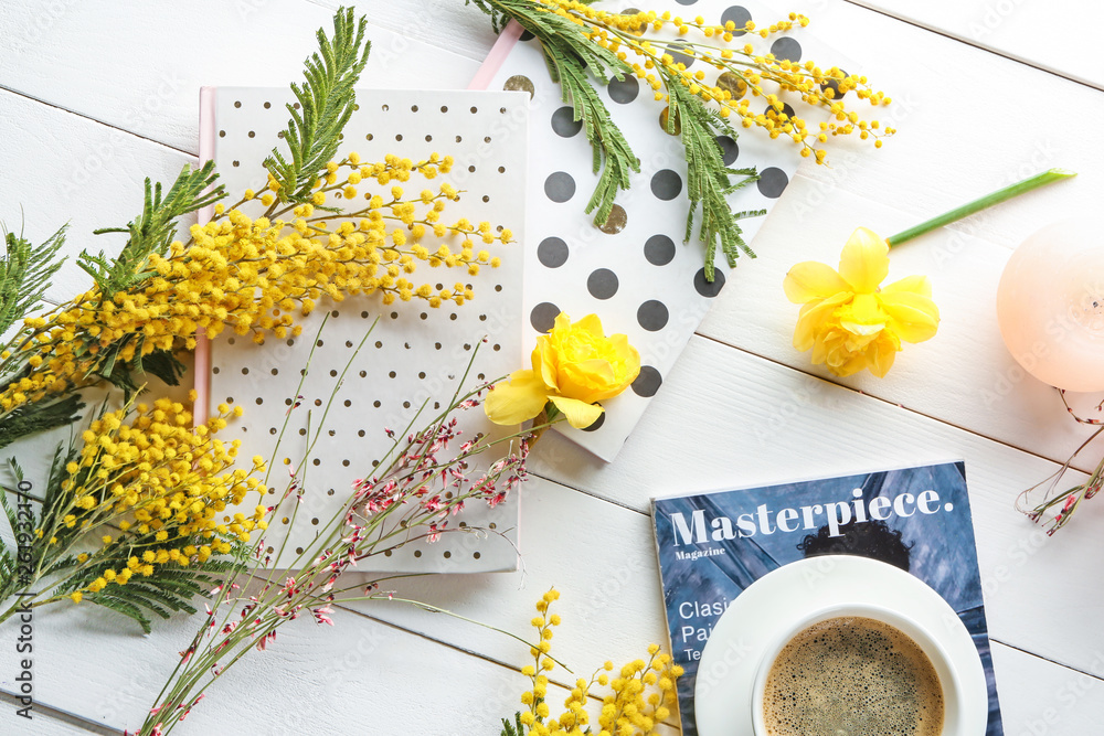 漂亮的黄色花朵，白色桌子上放着笔记本、一杯咖啡和时尚杂志