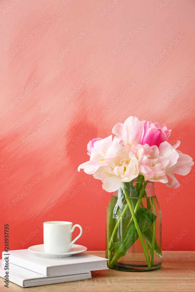 在彩色背景下，桌子上放着漂亮的郁金香、书籍和一杯咖啡的花瓶