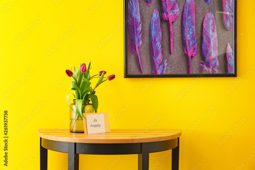 彩色墙附近桌子上放着漂亮郁金香的花瓶