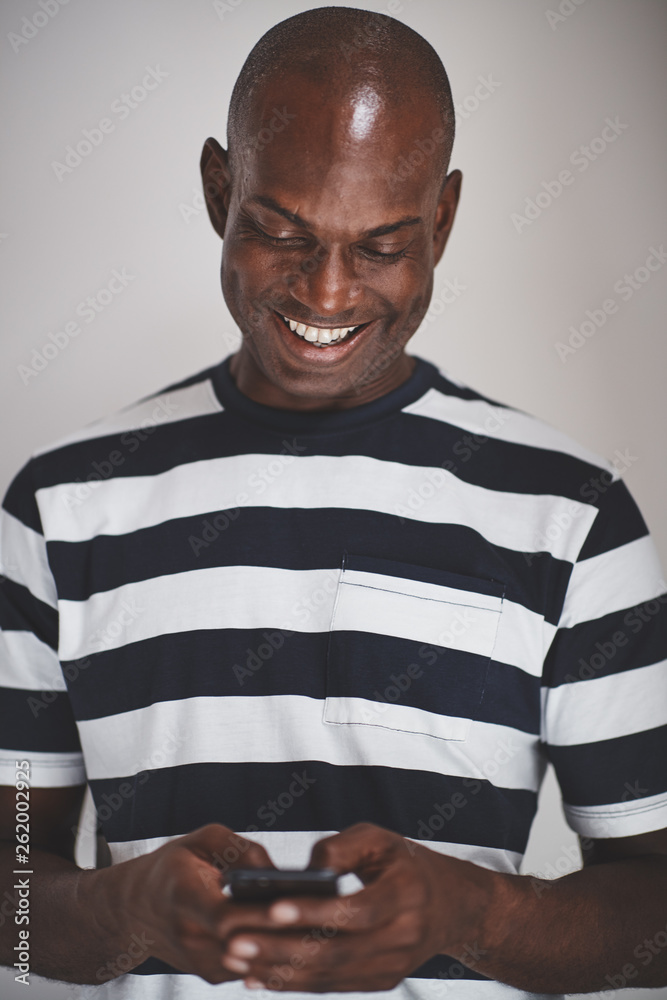 Smiling African entrepreneur using his cellphone against a gray