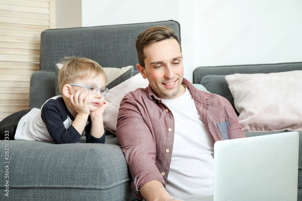 Young father with little son watching cartoons at home