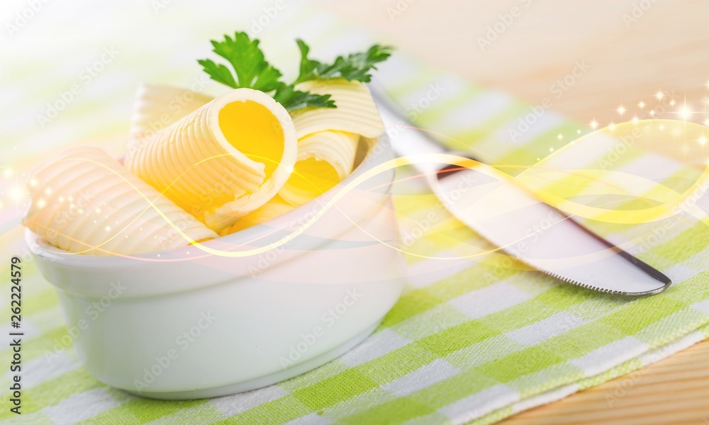 在方格餐巾上的白色碗中切片的新鲜黄油