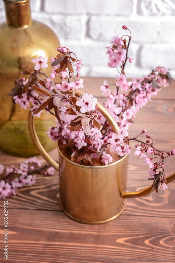 木桌上有美丽的开花树枝的水罐