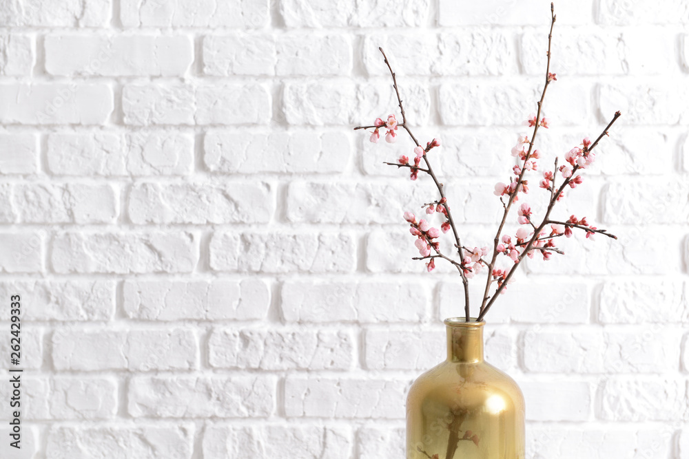 白色砖墙衬托下，花瓶上有美丽的开花树枝