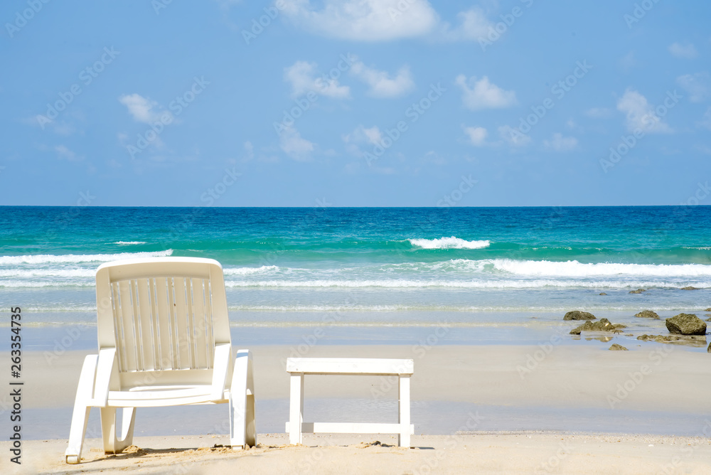 面朝大海的海滩海景。白色沙滩椅和小桌子放在海滩上。