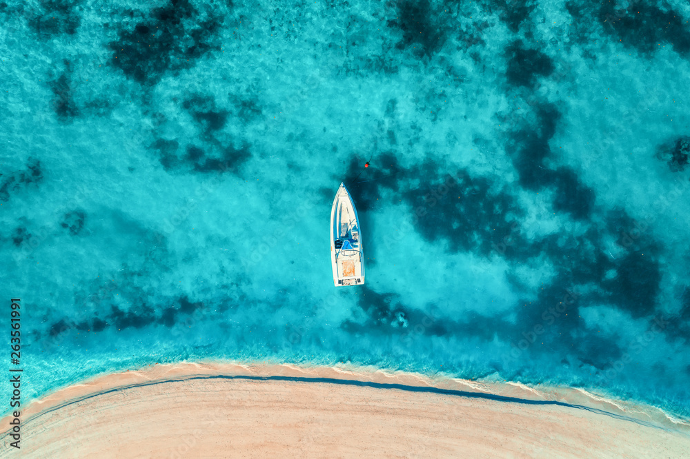 Aerial view of the white yacht in the clear blue water at sunset in summer. Top view from drone of b