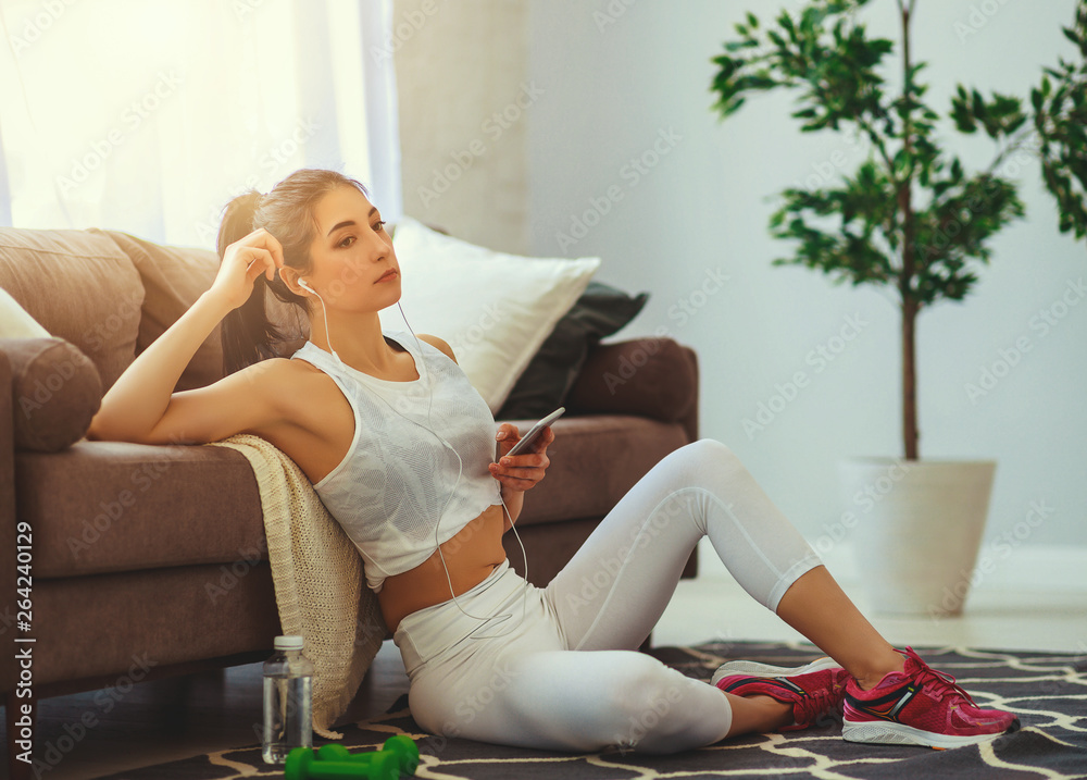 girl doing sports fitness at home resting and drinking water.