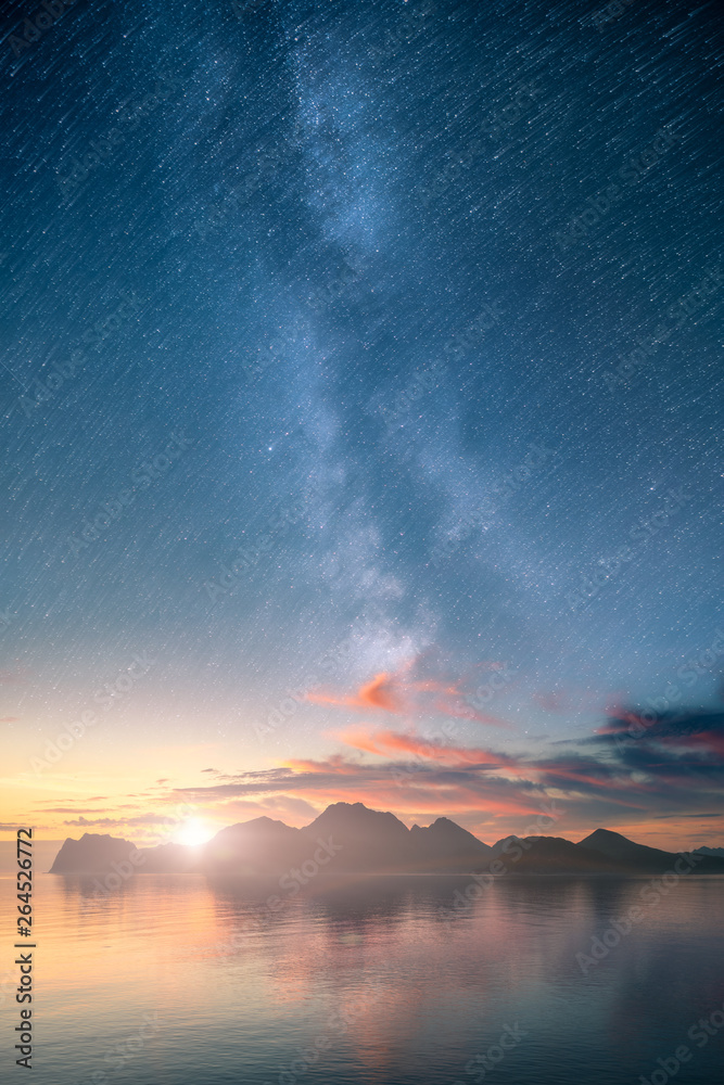 Beautiful vertical view of an ocean and mountains with epic milky way on the sky and star trail effe