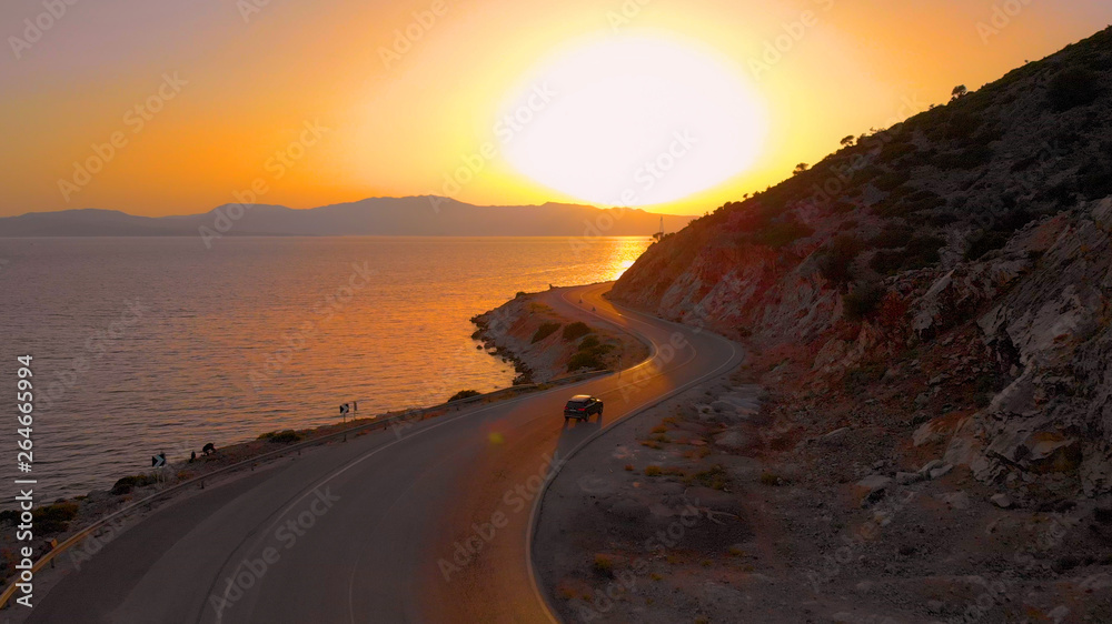 无光：金色的日落照亮了海边，汽车沿着风景优美的道路行驶。