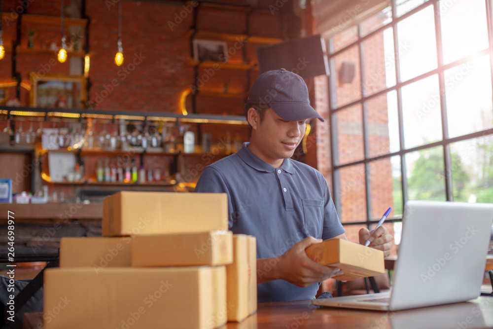 网上购物的年轻人在工作中用纸板箱做小生意。卖家正在准备产品