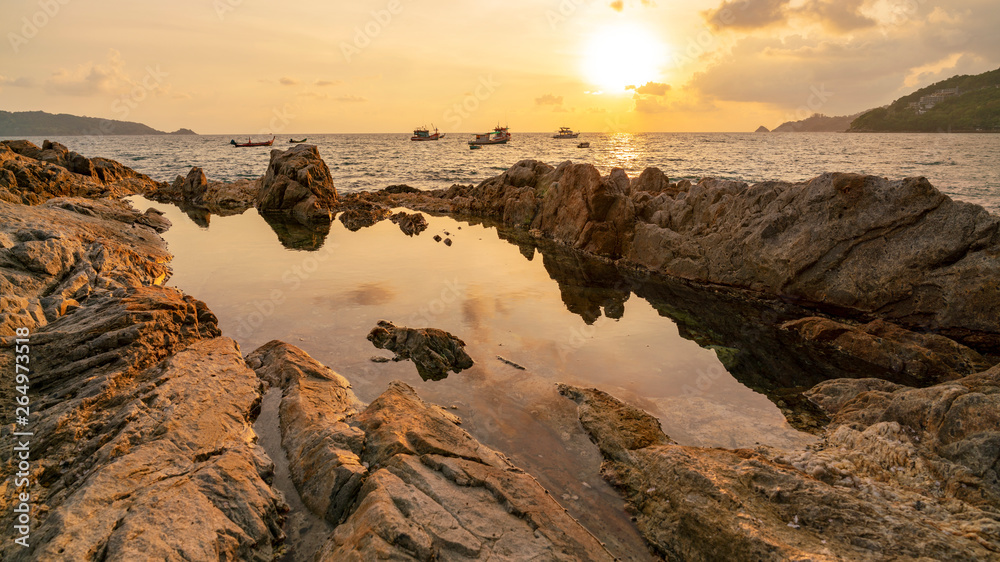 戏剧性的天空和波浪海景的长曝光图像，日落背景为岩石
