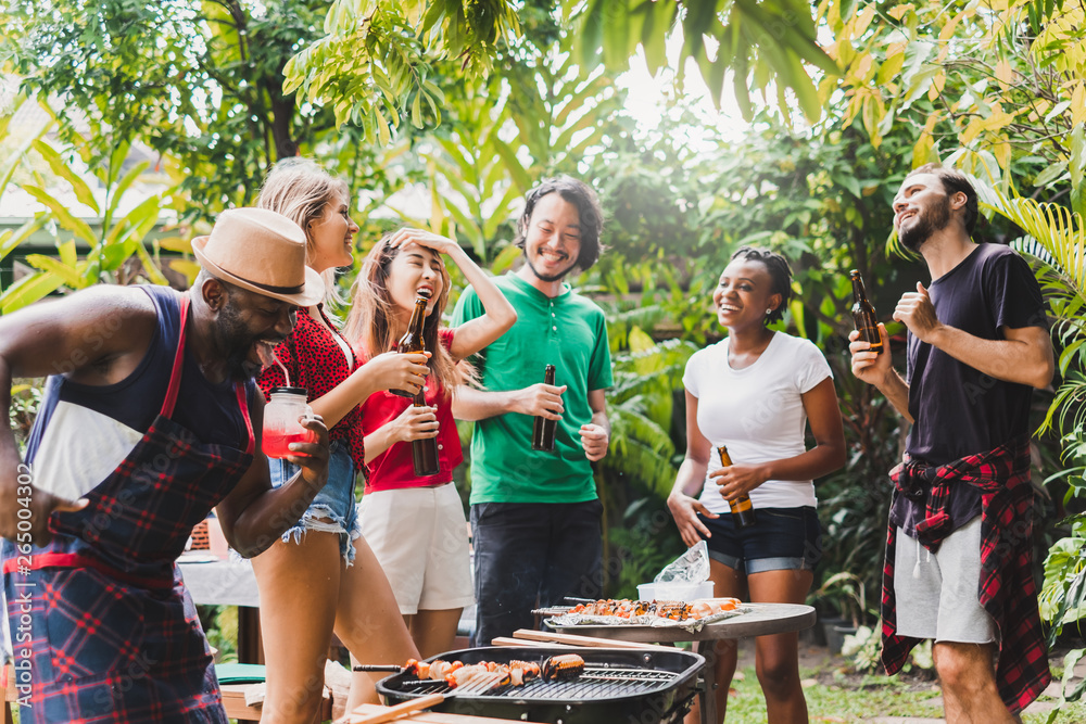 一群多元化的人在家里举行烧烤/烧烤派对，为午餐烹饪烤肉/牛肉