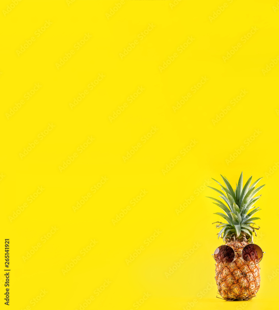 夏日度假，戴着太阳镜和贝壳的创意菠萝抬头看黄色背景