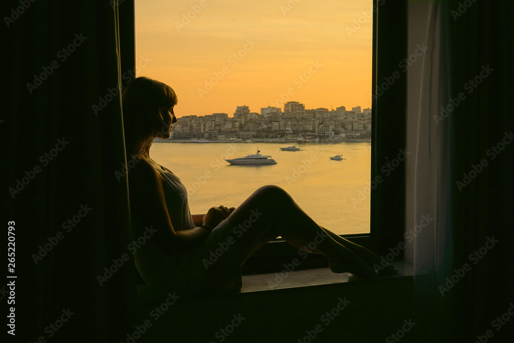 CLOSE UP: Woman sitting on a window sill, observing calm landscape of Sarande.