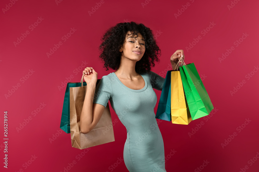 年轻的非裔美国妇女，彩色背景带着购物袋