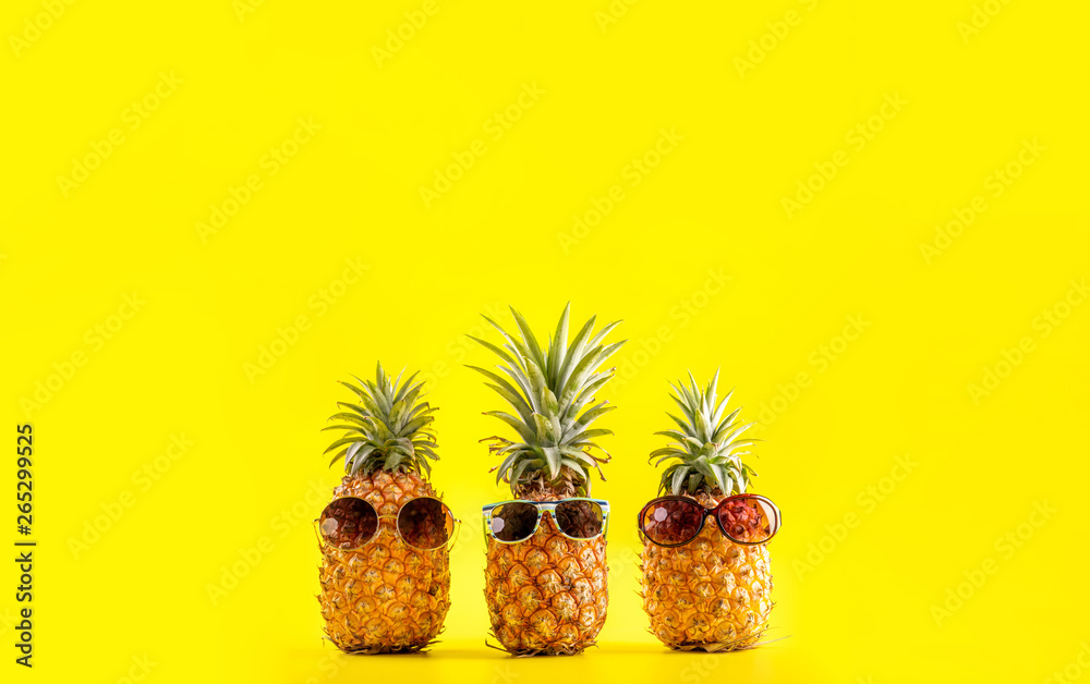 夏日度假，戴着太阳镜和贝壳的创意菠萝抬头看黄色背景