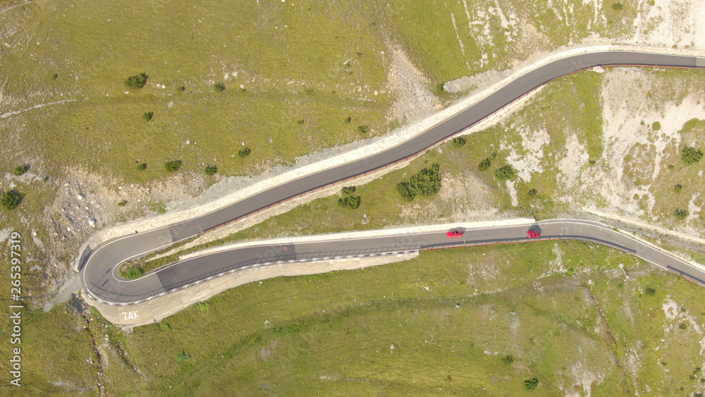 无人机：飞越意大利多洛米蒂一条弯曲道路上相遇的两辆红色汽车