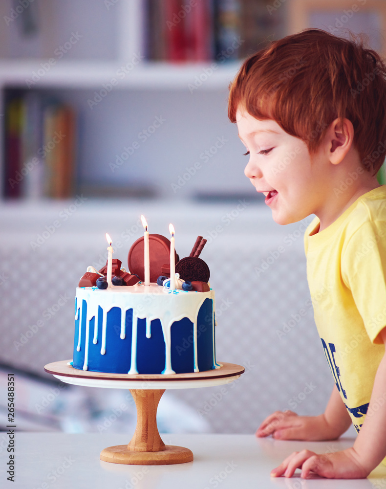 可爱的红发快乐男孩，孩子在三岁生日时在生日蛋糕上吹蜡烛