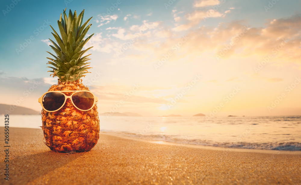 Pineapple with sunglasses on a sandy at tropical beach