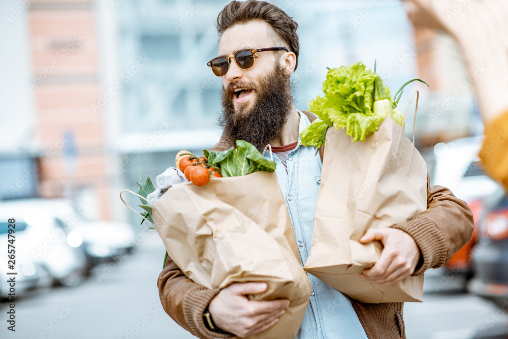 快乐时尚男士，超市附近的户外购物袋里装满了新鲜健康的食物