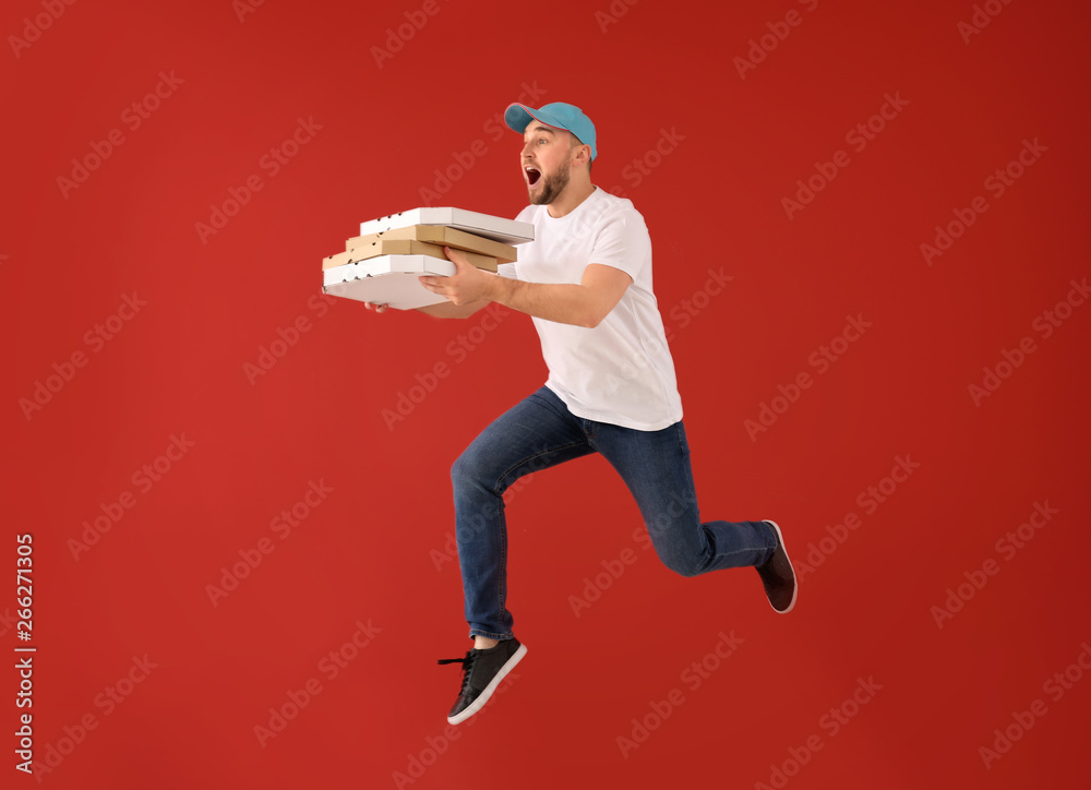 彩色背景上带披萨盒的跳跃男快递员