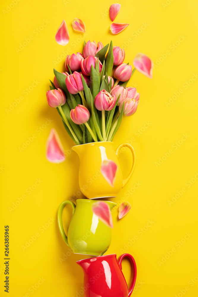完美的粉红色郁金香，装在黄色背景的彩色罐子里