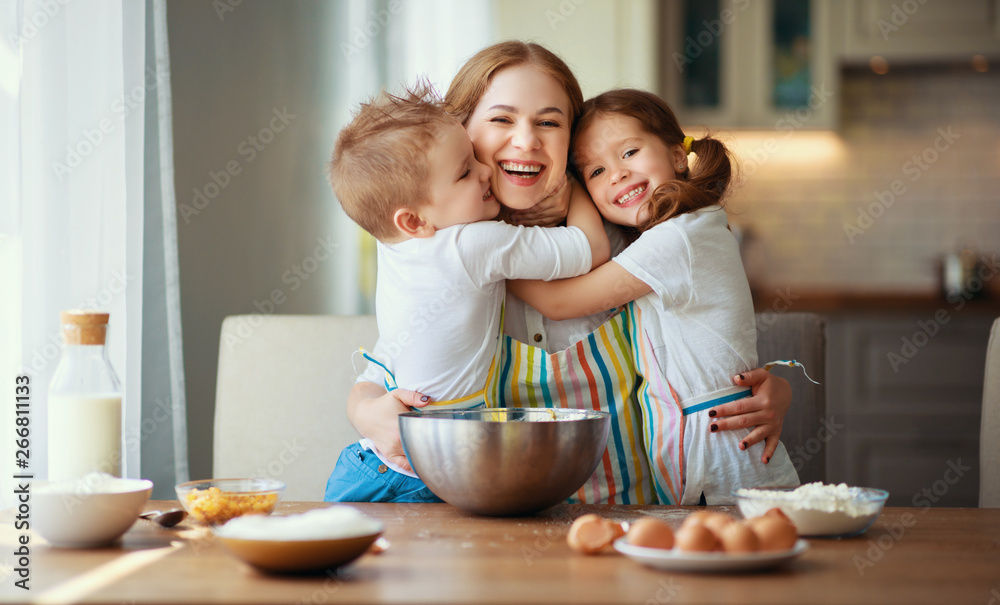 厨房里的幸福家庭。母亲和孩子们正在准备面团，烤饼干。