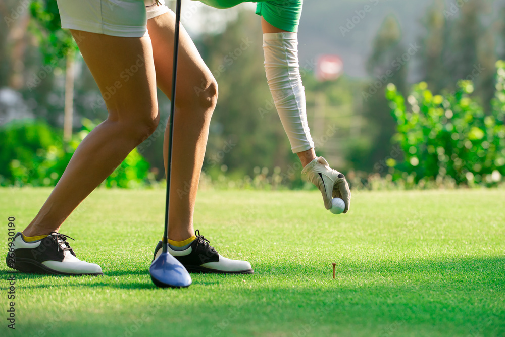 近距离观察女高尔夫球手在高尔夫球场将高尔夫球放在球座上，健康假期概念