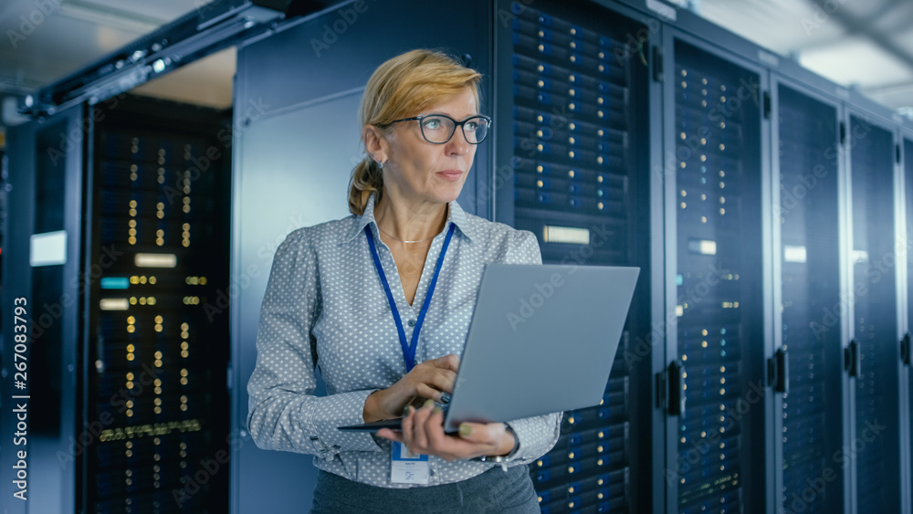 在数据中心：女性IT技术人员在笔记本电脑上运行维护程序，控制操作