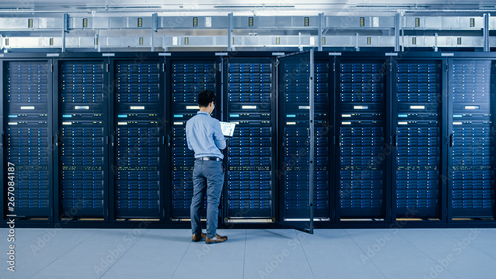 在现代数据中心：IT工程师站在开放式服务器机架机柜旁，做无线主控
